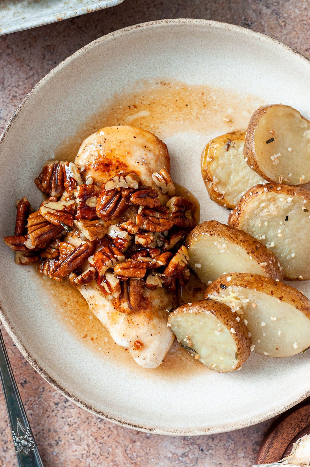 Main St Bistro roasted potatoes on a plate with a chicken breast and honey pecans